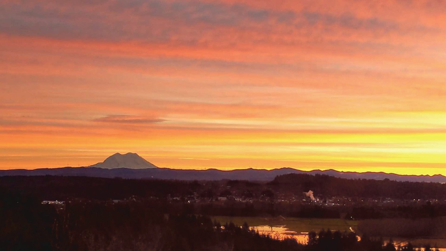 The sun rises over Chehalis Friday morning as Mount Rainier rises above the horizon.